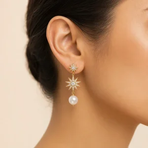 Close-up of a model wearing a gold starburst and pearl drop earring